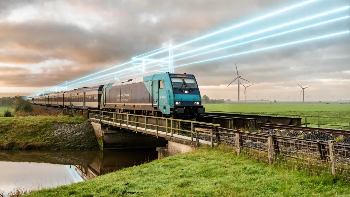 A train crosses a bridge in a scenic rural area with wind turbines and glowing blue lines in the cloudy sky, symbolizing modern technology and sustainability.